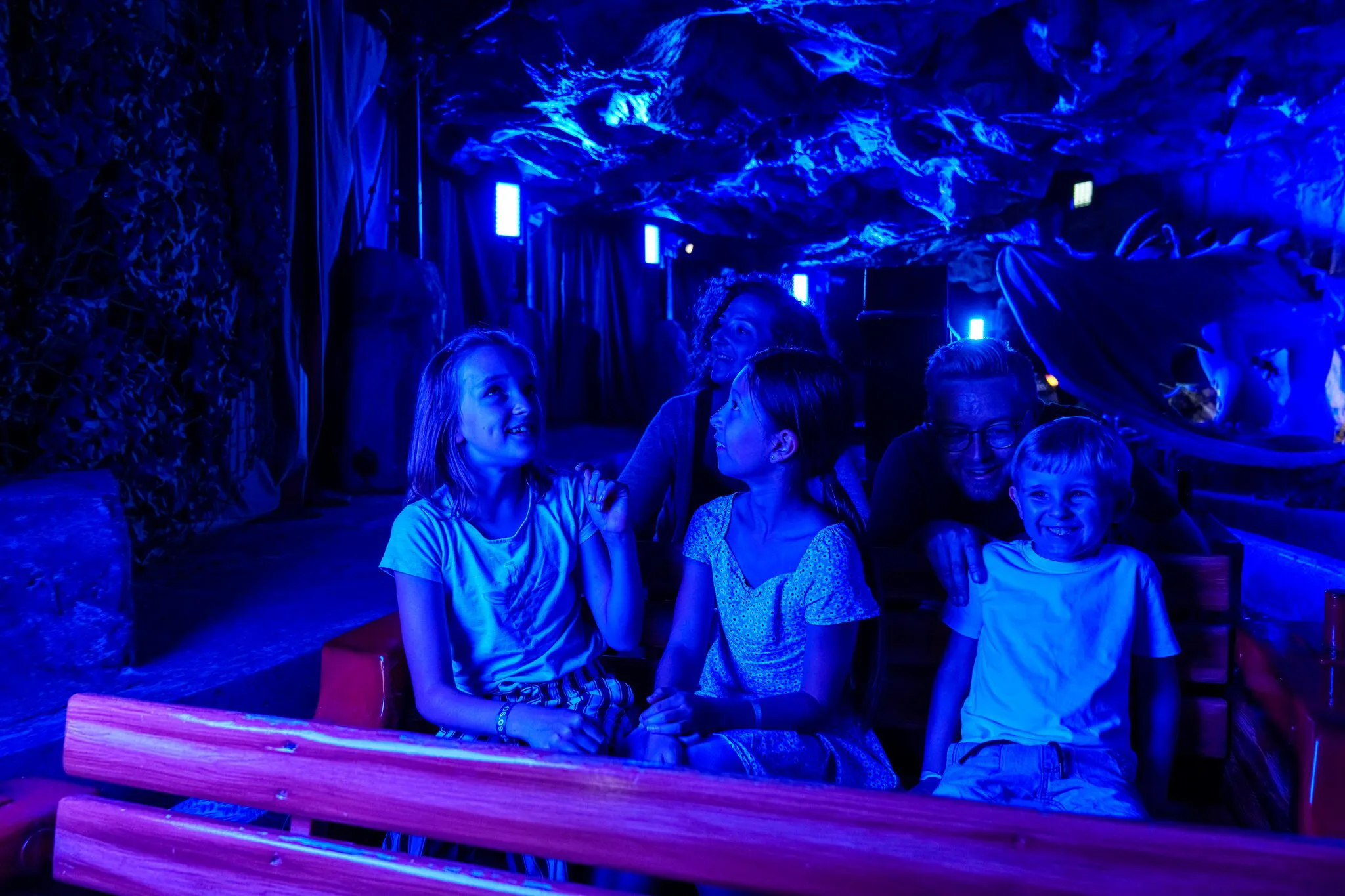 Eine fünfköpfige Familie sitzt im Boot der Drachengrotte im Heide Park Resort. Sie sind in der dunklen Höhle und schauen sich gespannt um.