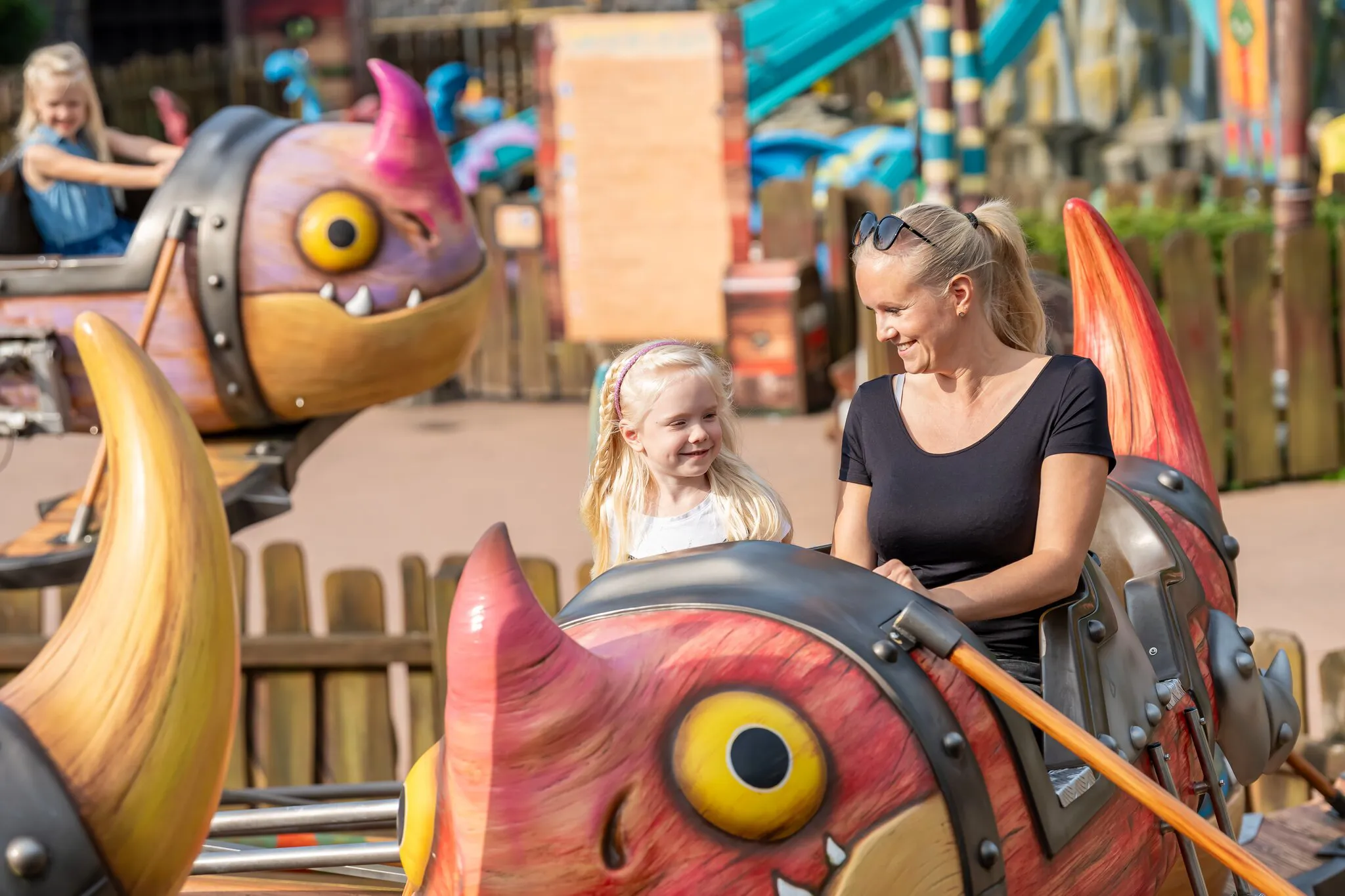 Eine Frau und ein Mädchen sitzen in der Gondel von Grobians Wolkenspringer im Heide Park Resort. Die Gondeln sind bunte Drachen.