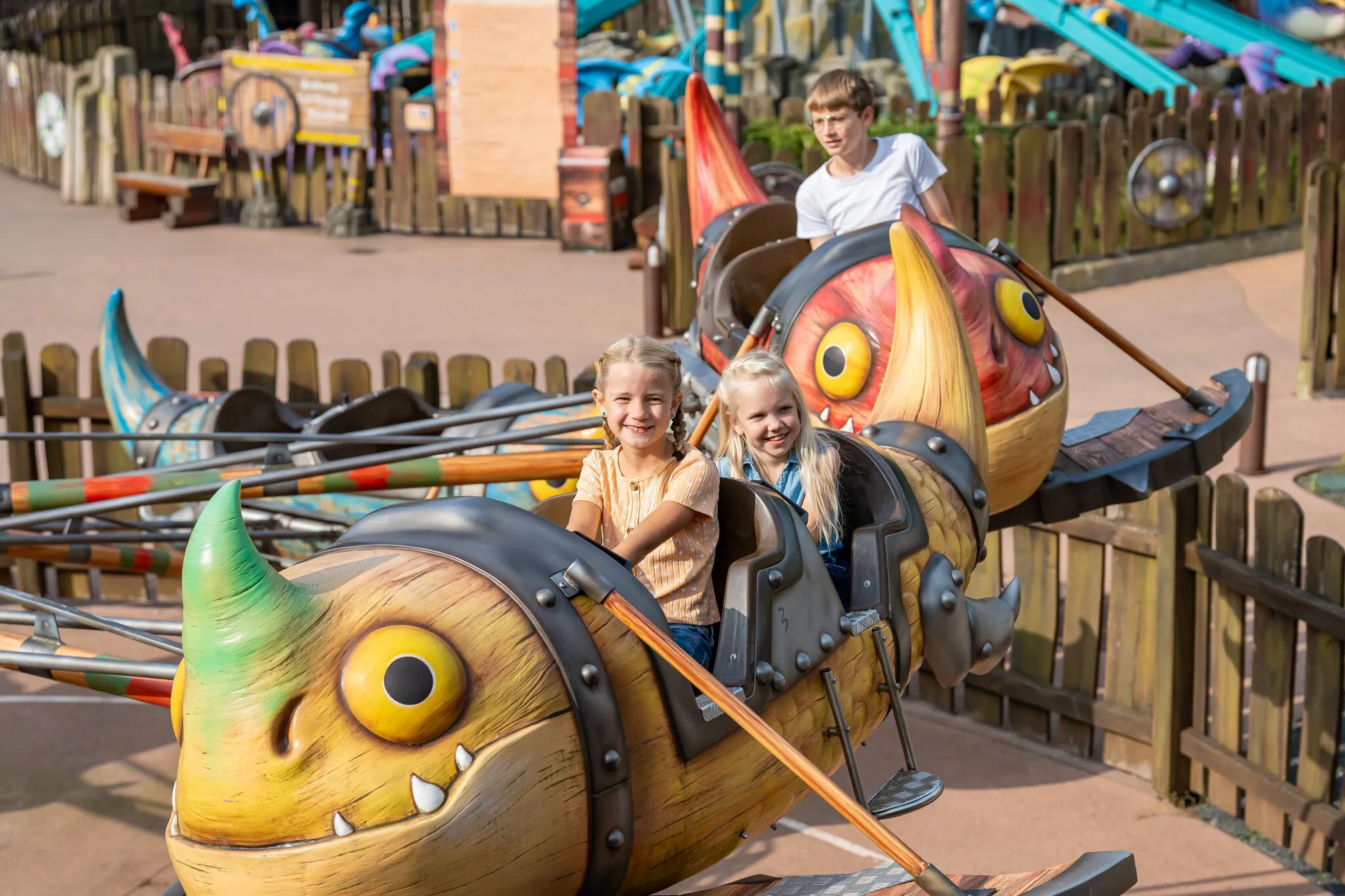 Zwei fröhliche Mädchen sitzen in der Gondel von Grobians Wolkenspringer im Heide Park Resort. Die Gondeln sind bunte Drachen.