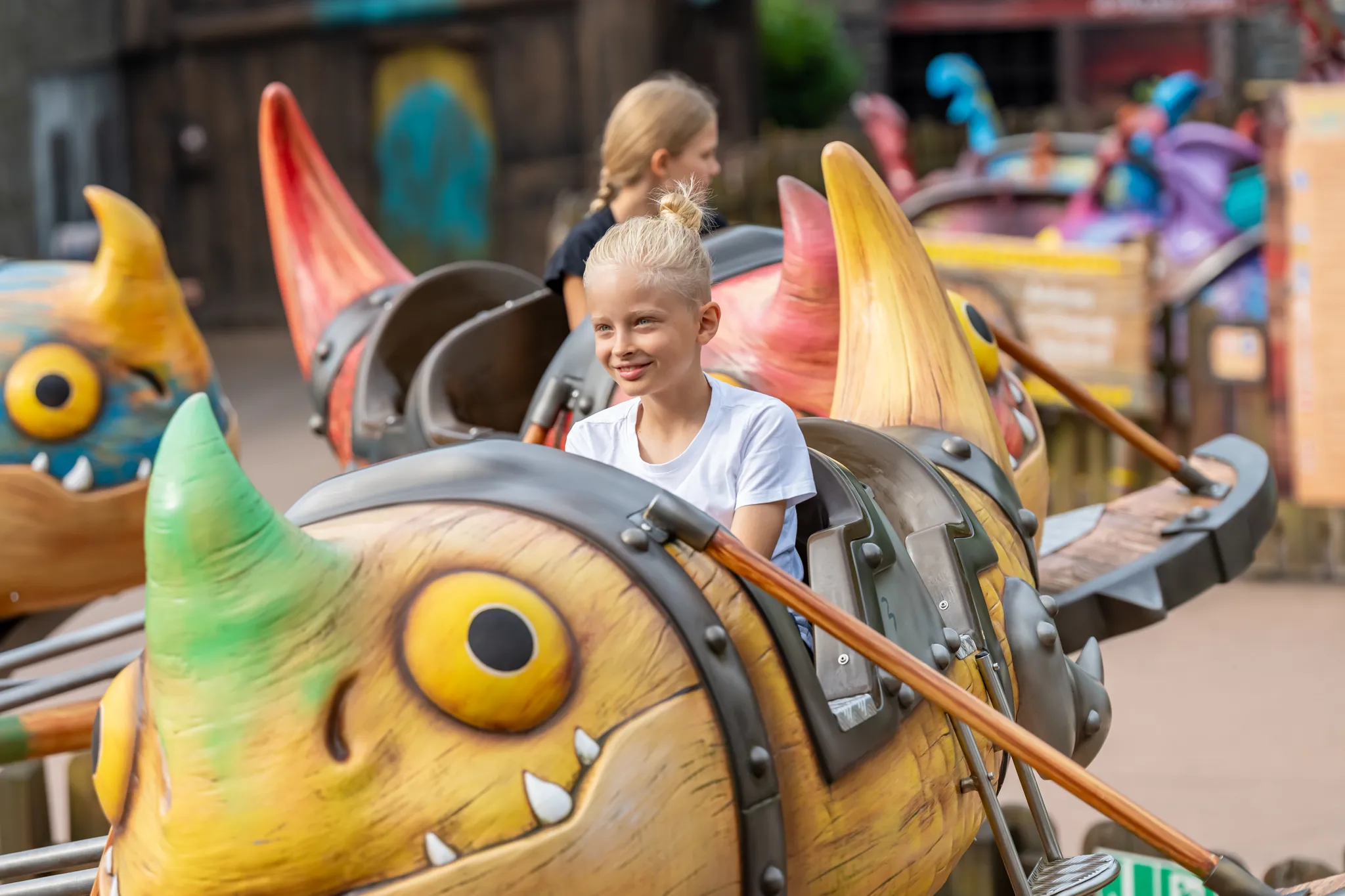 Ein fröhlicher Junge sitzt in der Gondel von Grobians Wolkenspringer im Heide Park Resort. Die Gondeln sind bunte Drachen.