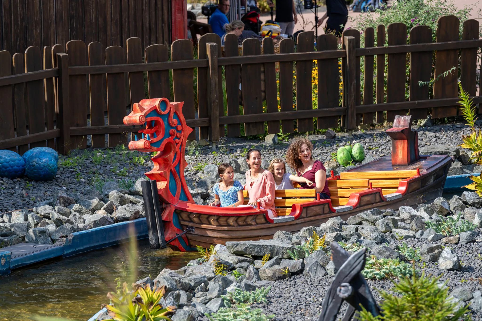 Zwei Frauen und zwei Mädchen sitzen im Wikingerboot und fahren durch eine steinige Landschaft im Heide Park Resort
