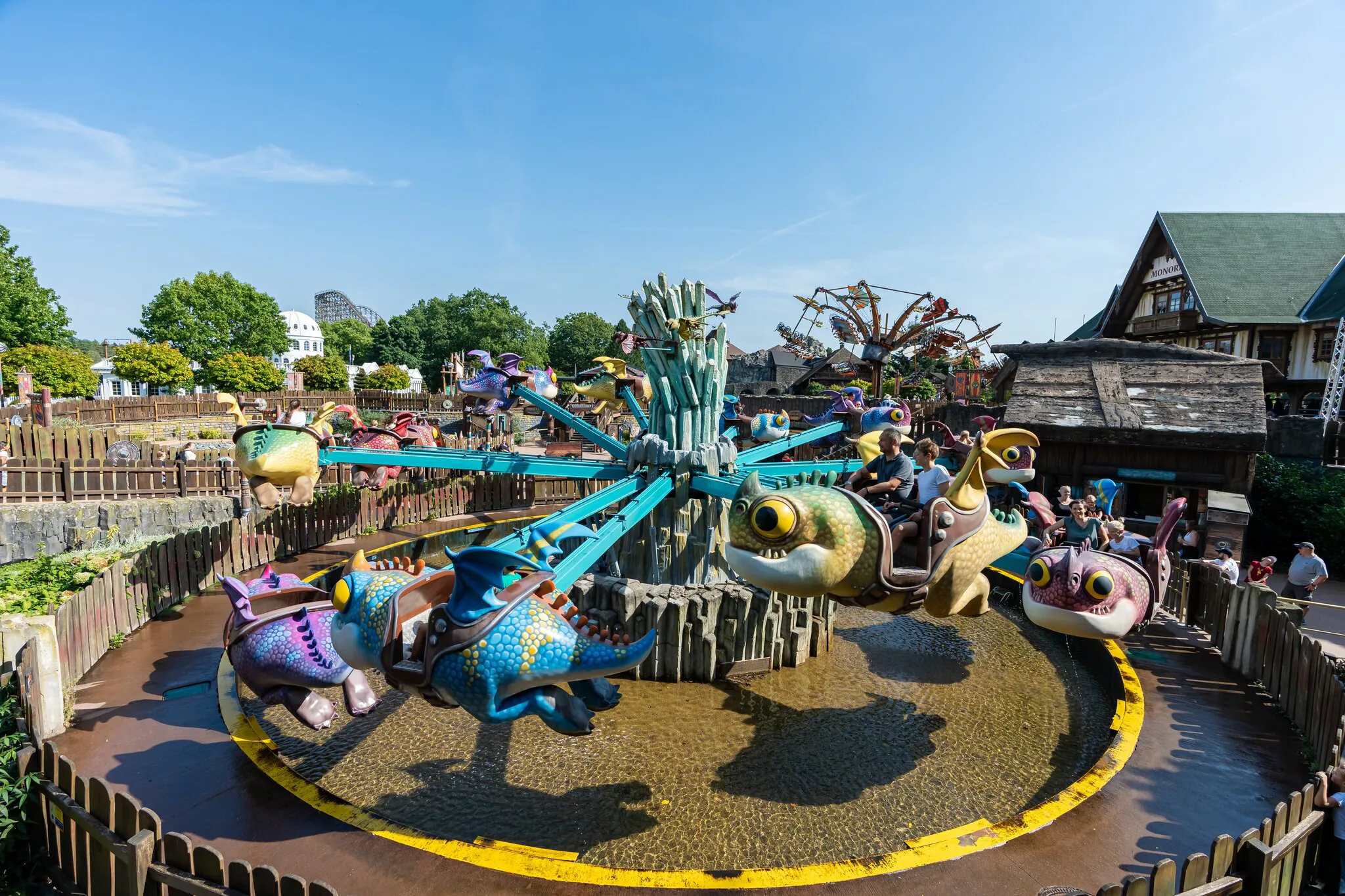 Kinder fahren in fliegenden Drachen über Wasser im Themenbereich „Drachenzähmen – Die Insel“ im Heide Park Resort.