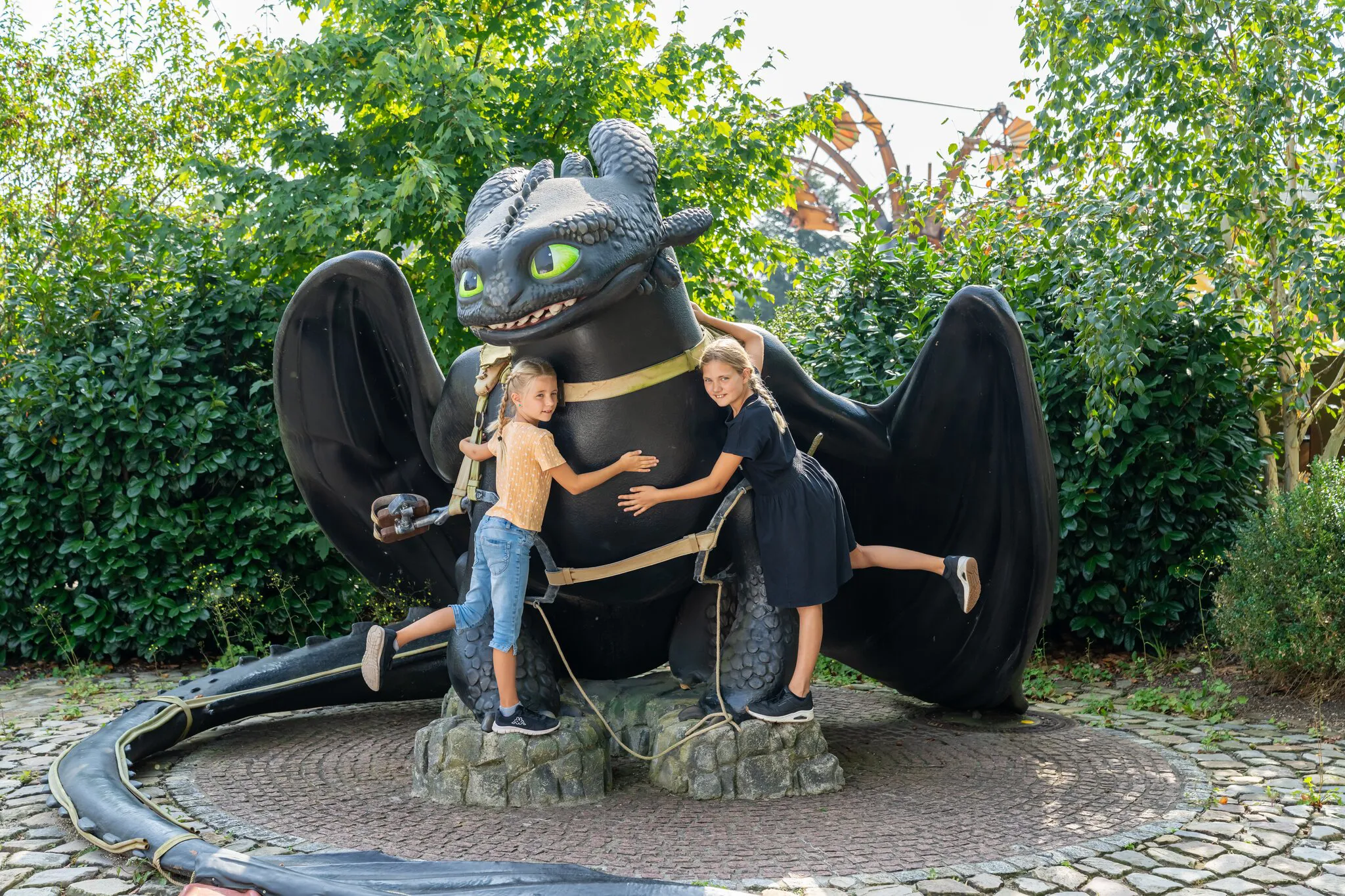 Zwei Mädchen umarmen einen großen Ohnezahn.