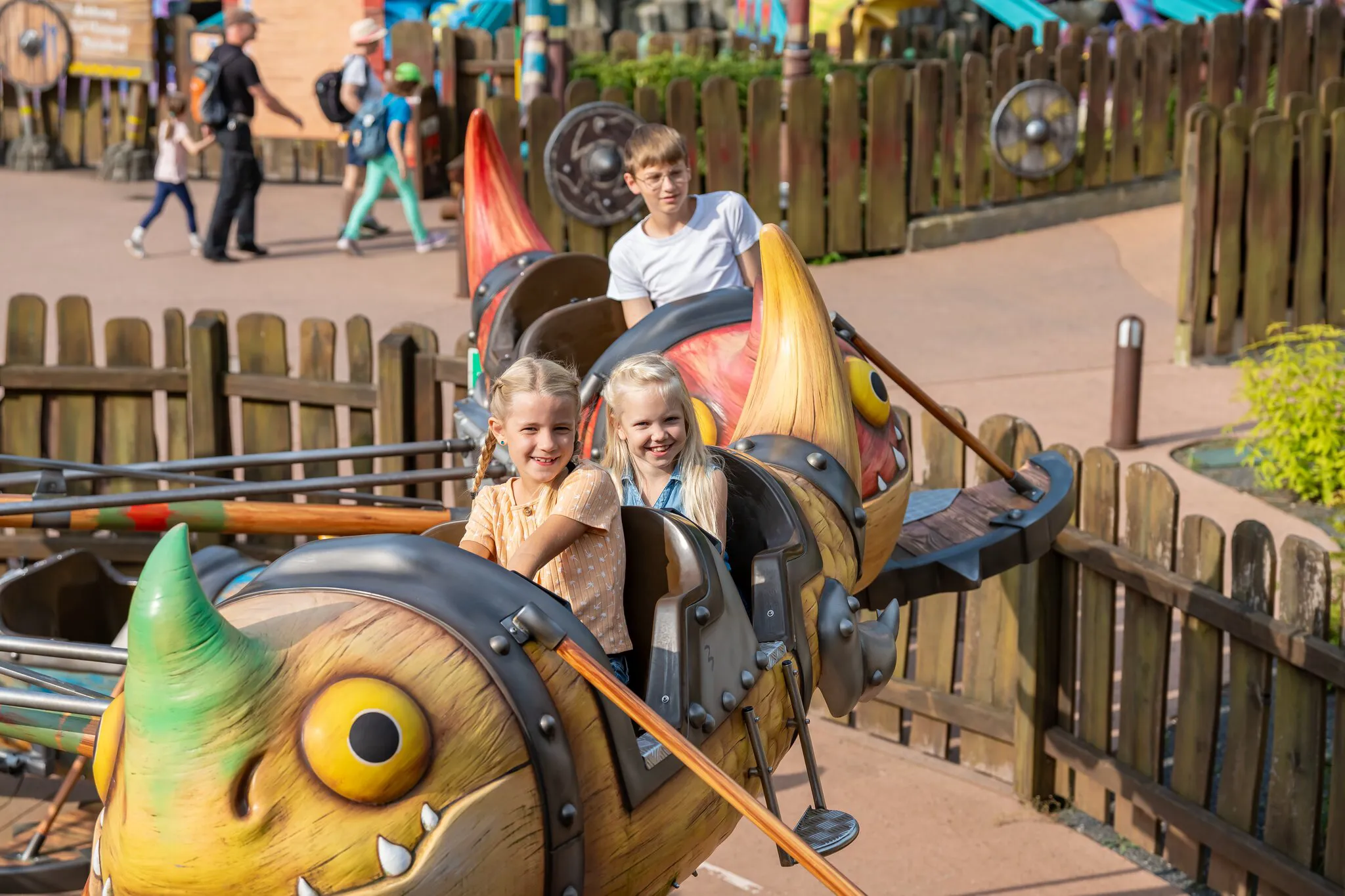 Zwei fröhliche Mädchen sitzen in der Gondel von Grobians Wolkenspringer im Heide Park Resort. Die Gondeln sind bunte Drachen.