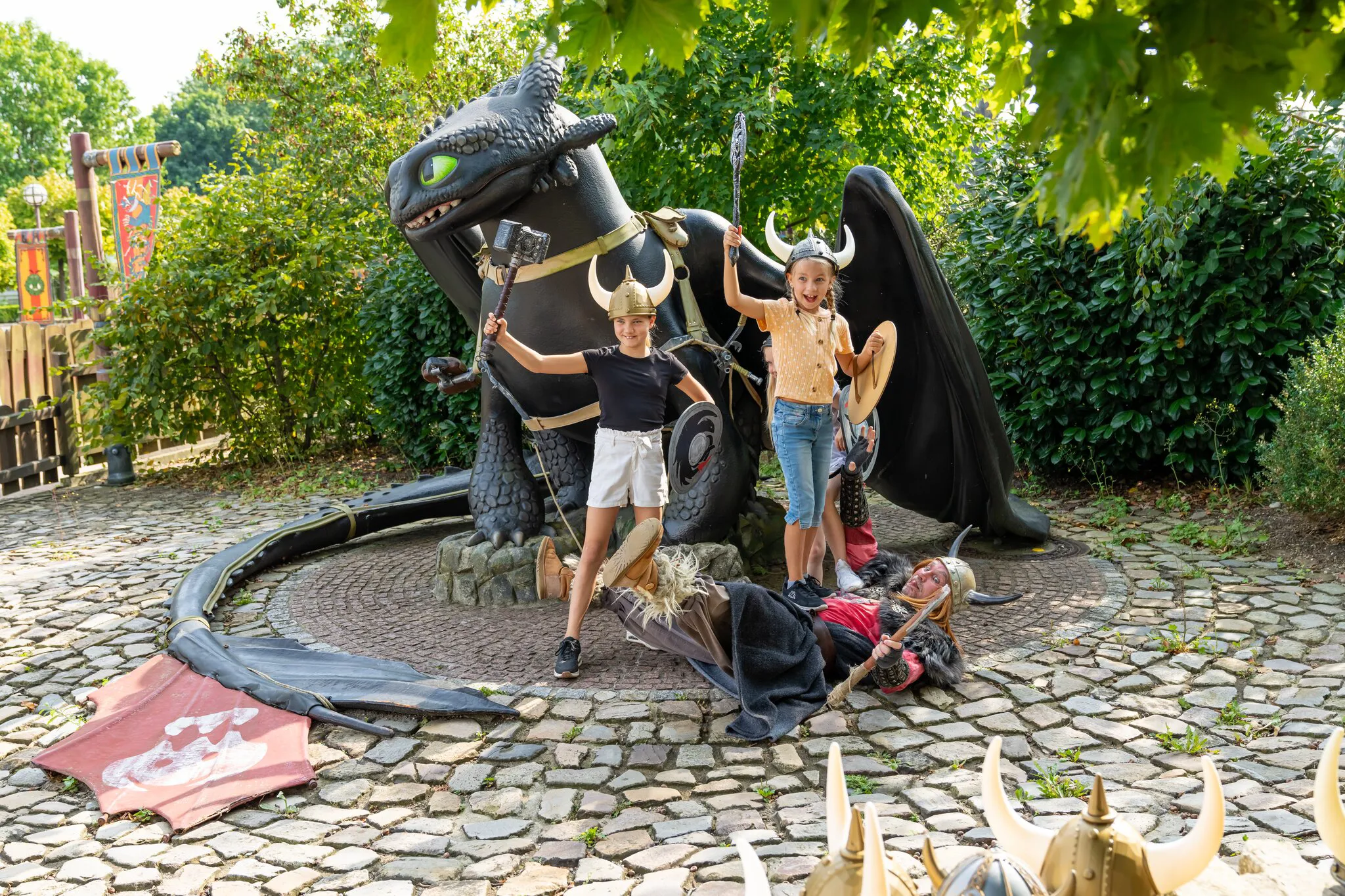 Zwei Mädchen spielen mit einem Wikinger bei einer großen Ohnezahn-Figur.